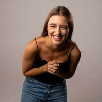 Thumbnail for Smiling woman wearing a black top and denim skirt, showcasing joy and warmth in her expression.