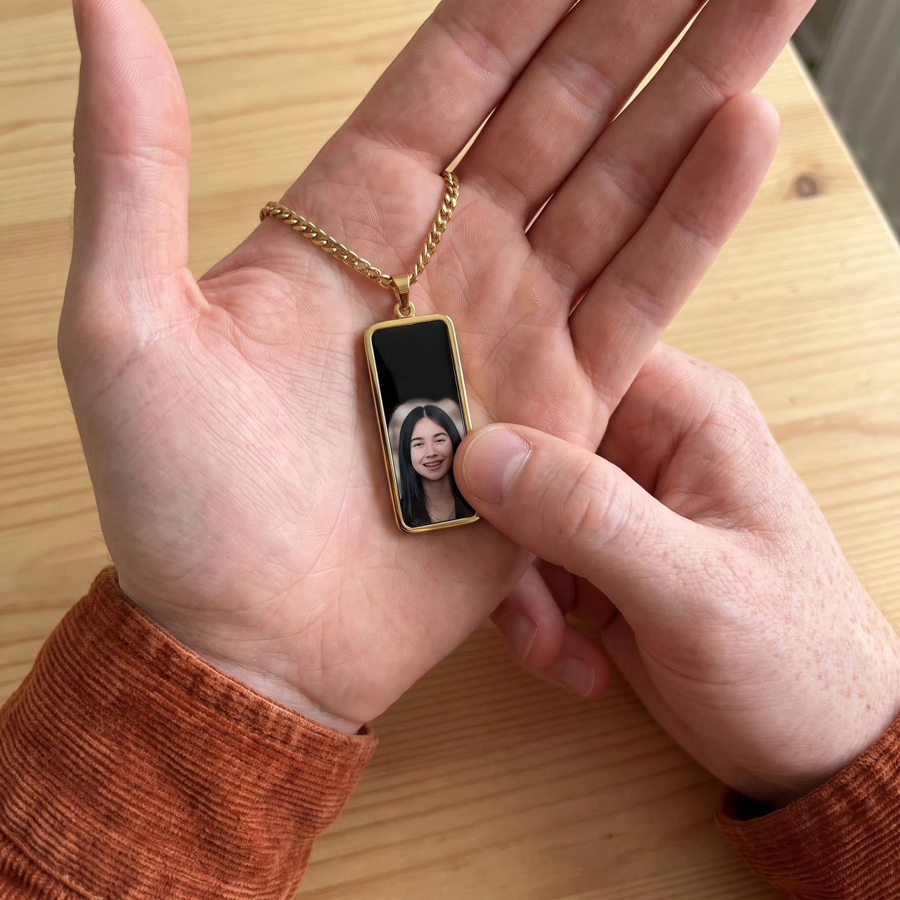 Thumb warming the gold bar pendant: the hidden photo appears under the thumb while the rest stays black | SKU: TPH-BARN-GOLD
