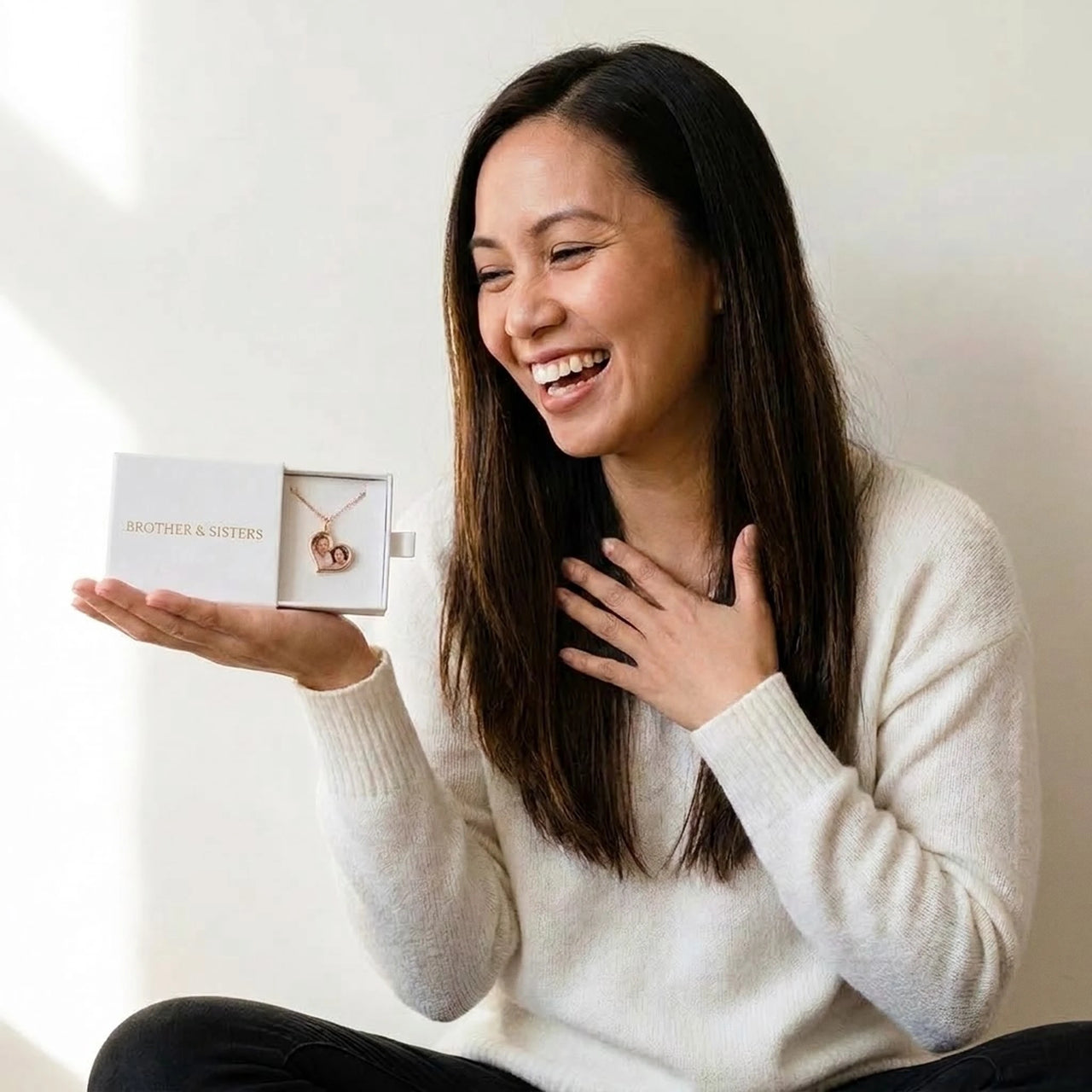 Woman laughing with joy as she finds her parents' photo in the rose gold heart necklace, small gift box in her palm | SKU: TPH-HRTN-ROSEGOLD